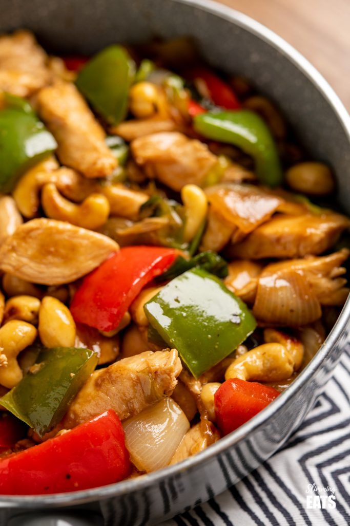 a pan filled with chicken, peppers and cashews on top of a table