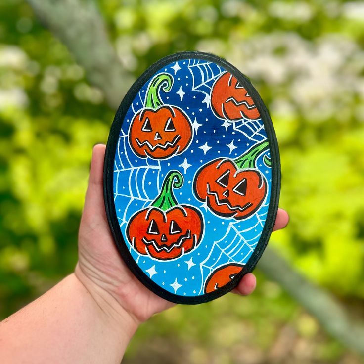 a hand holding up a painted plate with jack - o'- lanterns on it