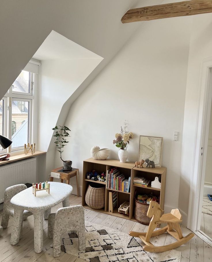 a living room filled with furniture next to a wooden table and bookshelf on top of a hard wood floor