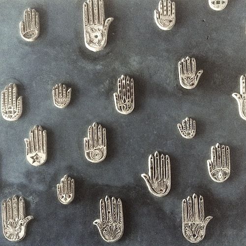 many small metal hand prints on a black surface