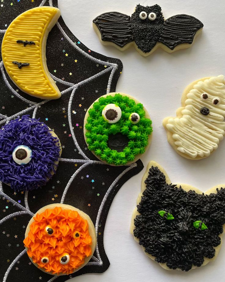 decorated cookies are arranged in the shape of bats and pumpkins with eyes on them