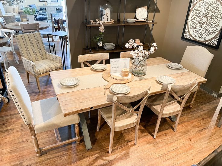 a dining room table with chairs and plates on it in front of a display case