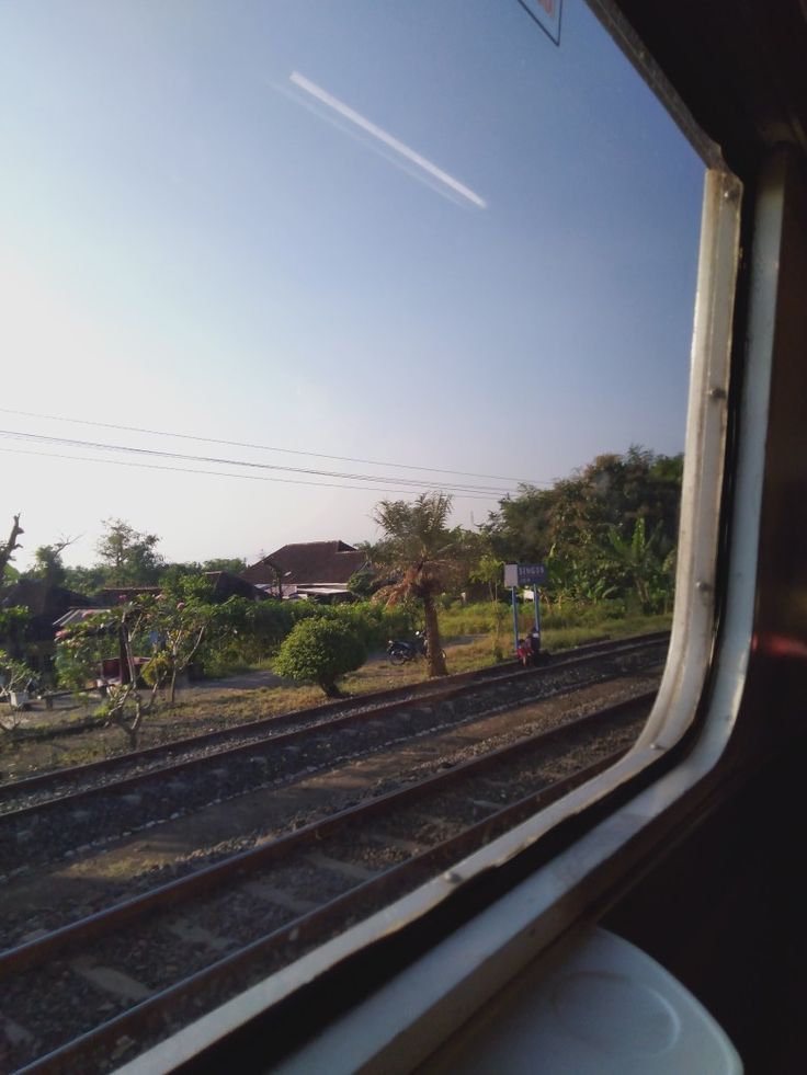 the view from inside a train window looking out at trees and houses