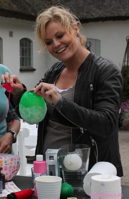 two women standing at a table with items on it and one woman holding a green ball