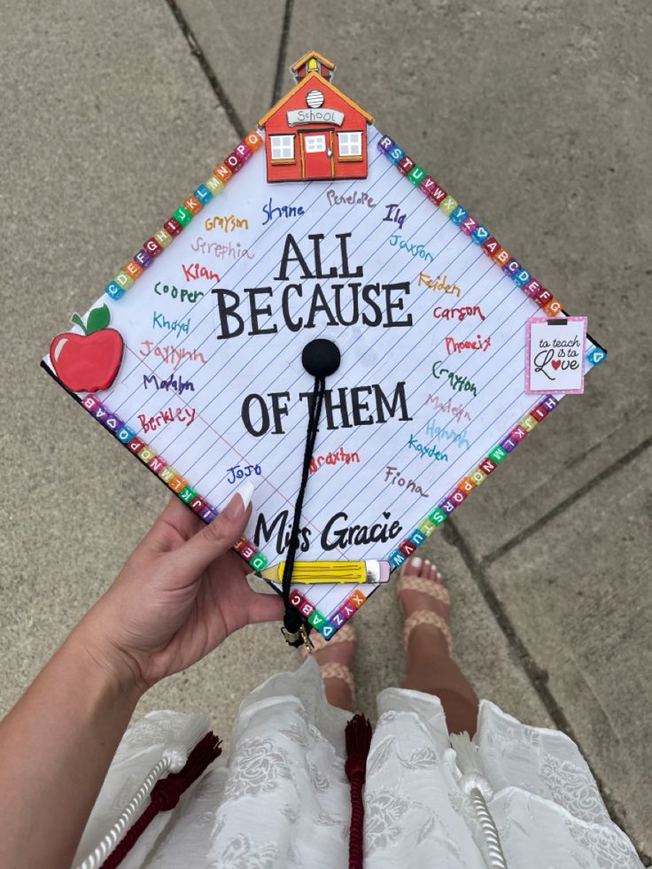 a person holding up a graduation cap that says all because of them with writing on it