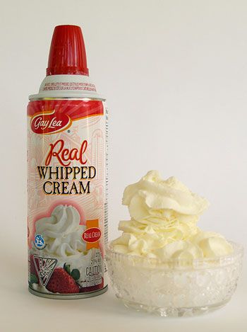 whipped cream in a bowl next to a can of real whipped cream on a white background