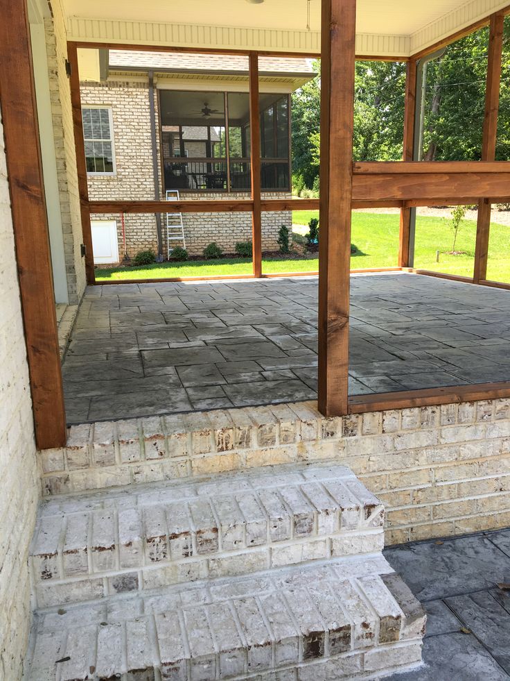 an empty porch with steps leading up to the front door and covered in wood posts