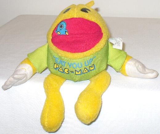 a yellow stuffed animal sitting on top of a white bed next to a wall with the words pac - man written on it