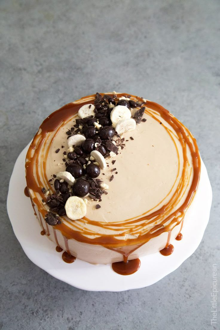 a cake with chocolate, bananas and caramel drizzled on top sitting on a white plate