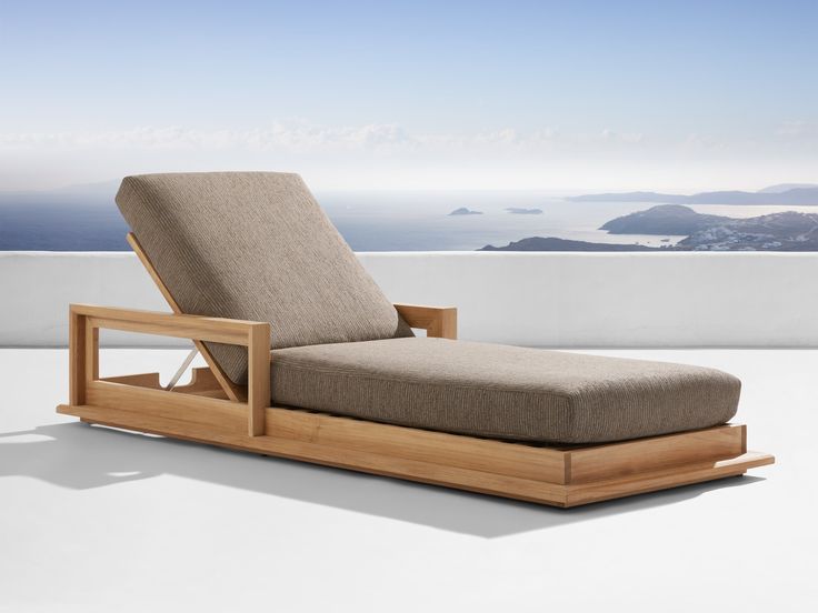 an outdoor chaise lounge chair sitting on top of a white floor next to the ocean