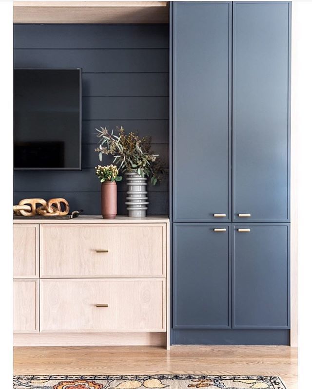 a living room with blue cabinets and a large flat screen tv mounted on the wall