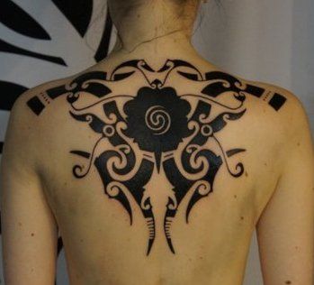 a woman with a tattoo on her back is standing in front of a black and white wall