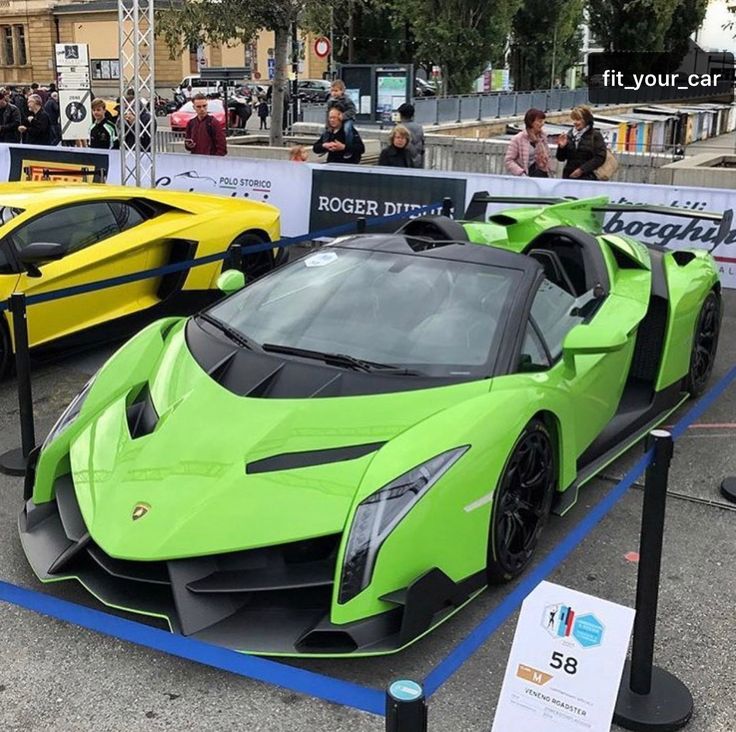 two green and yellow sports cars on display in a parking lot with people looking at them