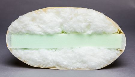 a half eaten sandwich with white bread and green tape on it's side, sitting on a gray surface