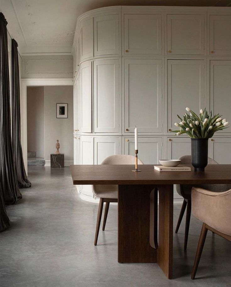 a dining room table with chairs and a vase filled with flowers