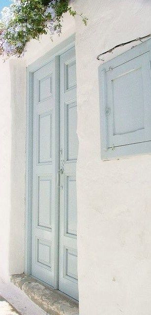 two blue doors are on the side of a white building