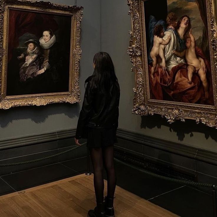 a woman standing in front of two paintings