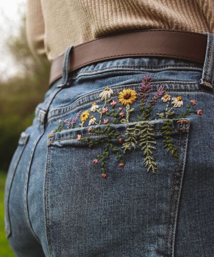 the back of someone's jeans with flowers embroidered on them and a brown belt