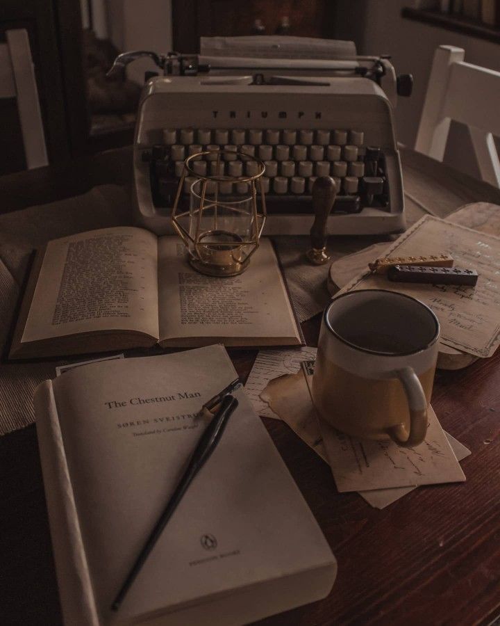 an old fashioned typewriter sitting on top of a table next to books and papers