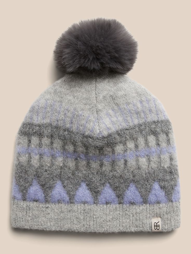 a grey and blue hat with a pom - pom on the top of it