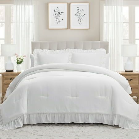 a white comforter with ruffled edges in a bedroom next to two framed pictures