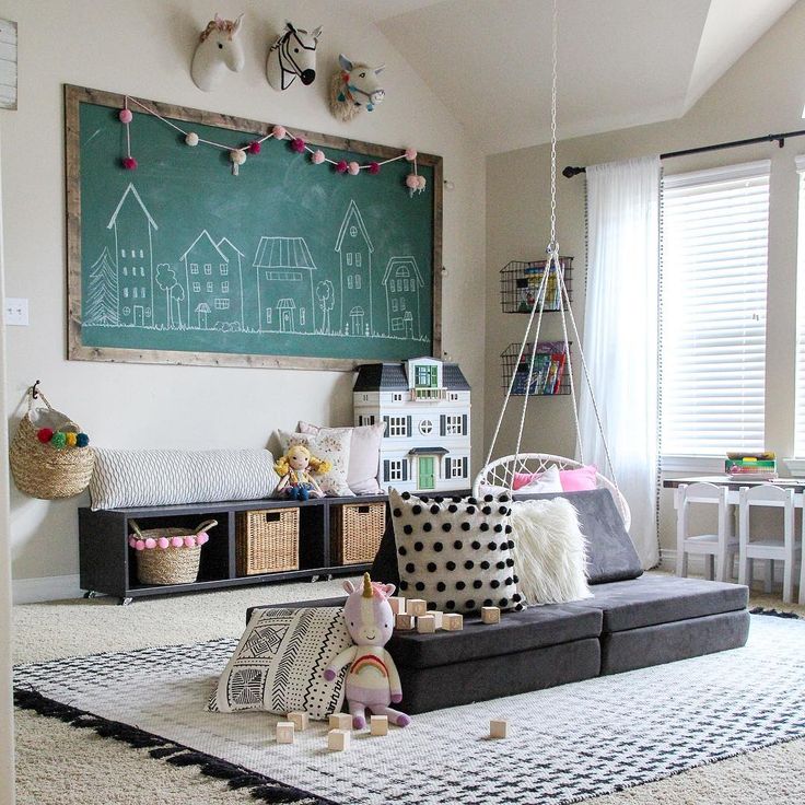 an instagram photo of a living room with toys on the floor and a chalkboard in the background