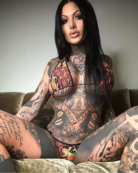 a tattooed woman sitting on top of a couch