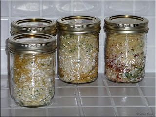 four jars filled with food sitting on top of a white tiled counter next to each other