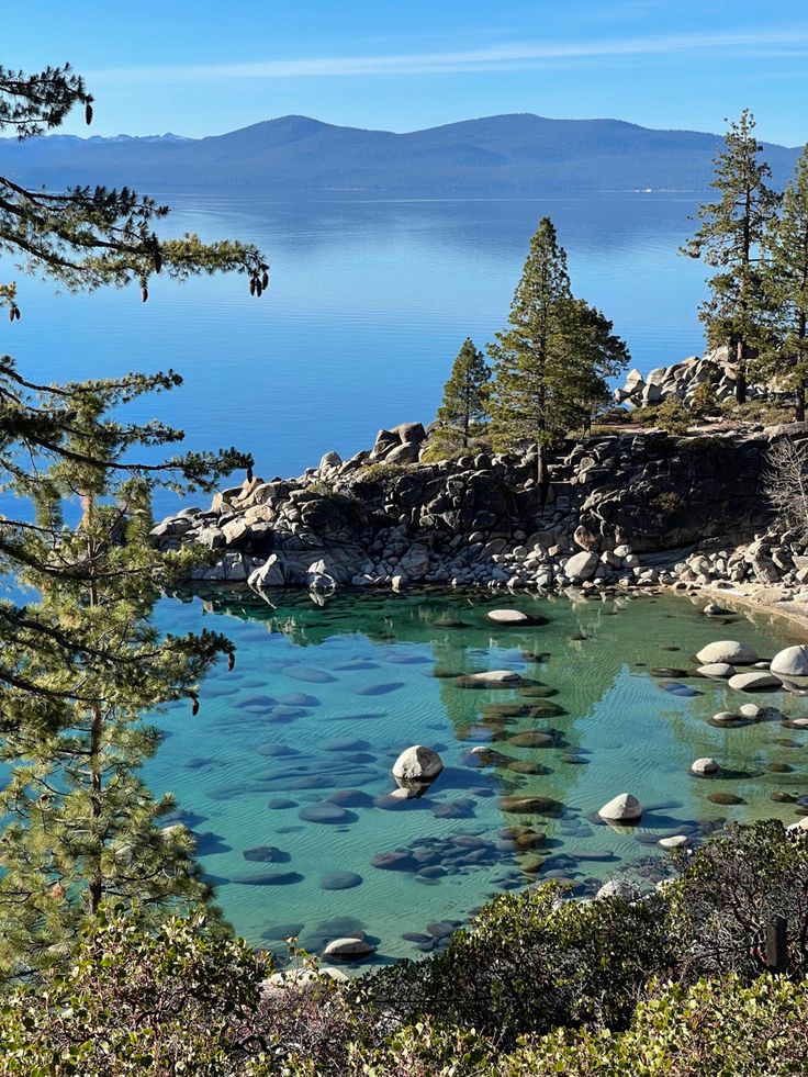 a lake surrounded by trees and rocks in the water