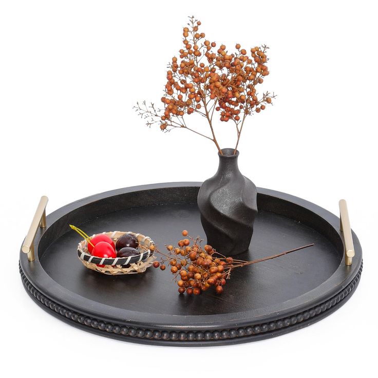 a black tray with some fruit and a vase on it