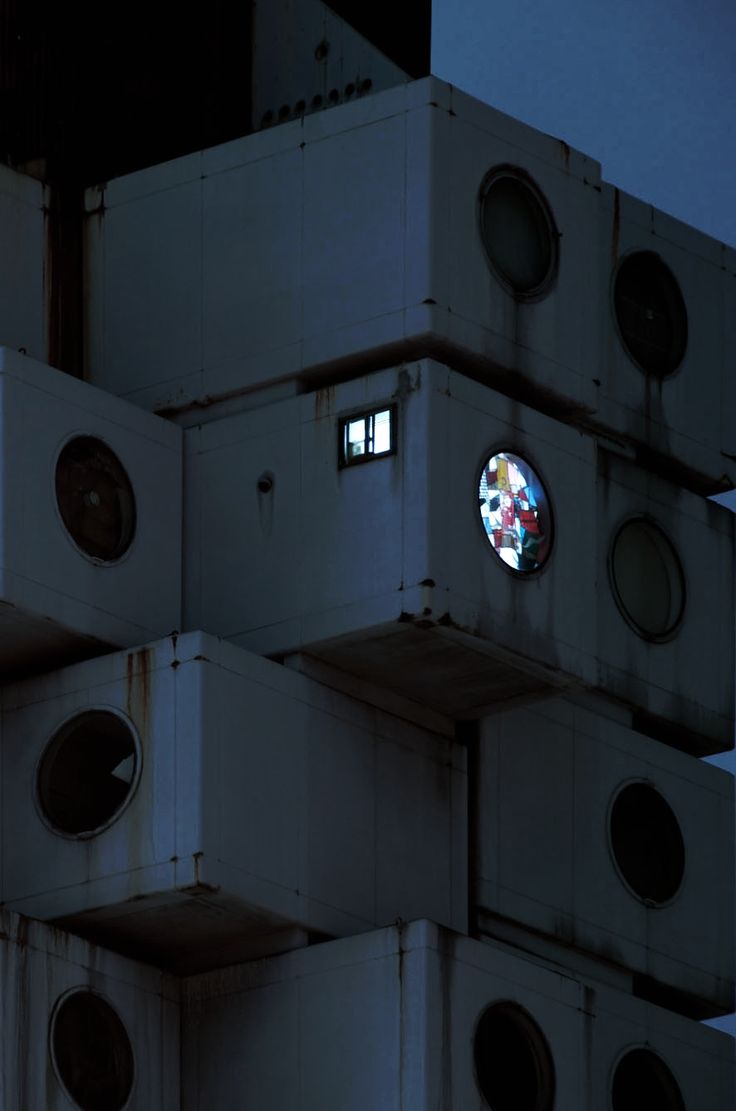 a round window is seen through the top of several stacked white boxes with holes in them