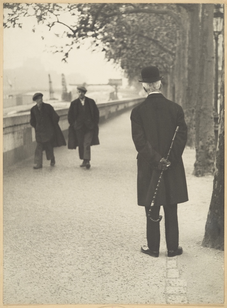 black and white photograph of two men walking down the street with canes in their hands