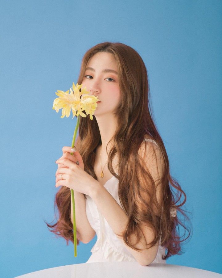 a woman with long hair holding a flower