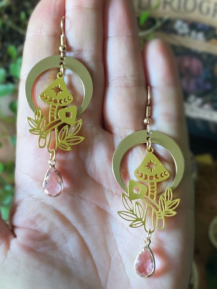 Beautiful handmade earrings with golden mushrooms, crescent moon charms and delicate baby pink glass crystals on golden ear wires🌙 Length: 8 cm  More beautiful jewelry can be found in my shop:  https://www.etsy.com/dk-en/shop/ONCEUPONAPOTIONDK?ref=seller-platform-mcnav&section_id=21367729 Should you have any questions please feel welcome to send me a message✨ Whimsical Brass Dangle Jewelry, Whimsical Brass Dangle Earrings, Whimsical Gold Earrings With Moon Charm, Whimsical Moon Charm Dangle Jewelry, Whimsical Dangle Moon Charm Jewelry, Whimsical Dangle Jewelry With Moon Charm, Whimsical Gold Metal Earrings, Whimsical Gold Jewelry With Mushroom Design, Whimsical Gold Jewelry For Pierced Ears