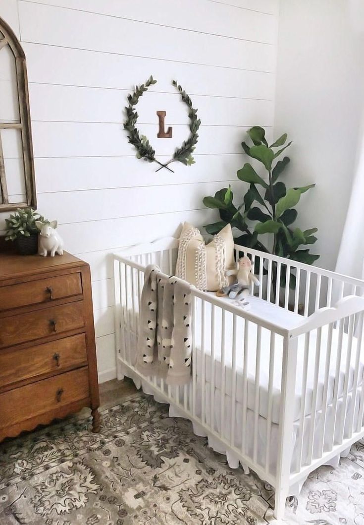 a white crib in the corner of a room next to a dresser and mirror