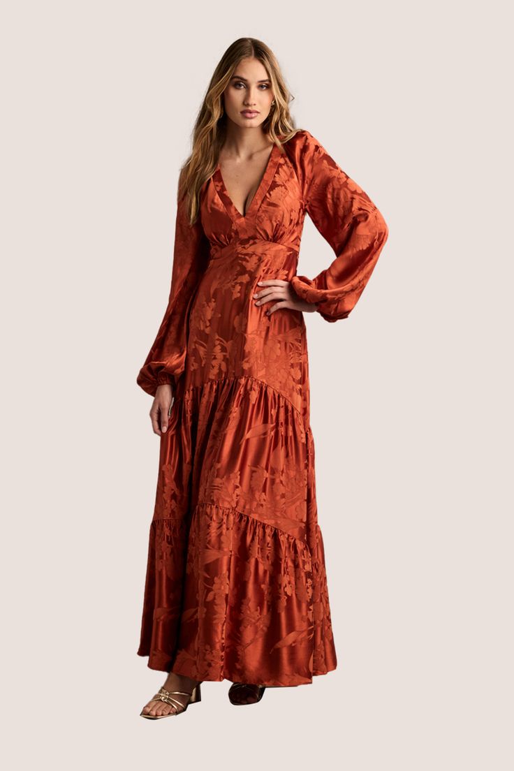 Take your formal wear to the next level in the Melissa Long Sleeve Maxi Dress. This stunning design features a flattering V-neckline, a keyhole back, and a flowy A-line skirt. The perfect style for any special occasion. Plus Size Fall Formal Dresses, Rust Prom Dress Burnt Orange, Flowy V-neck Maxi Dress For Cocktail, Fall V-neck Dress With Fitted Bodice, V-neck Midi Dress For Fall Wedding, Fall Wedding V-neck Midi Dress, Chic Surplice Neckline Dress For Gala, Formal Flowy V-neck Dress, Flowy V-neck Midi Dress For Wedding Guest