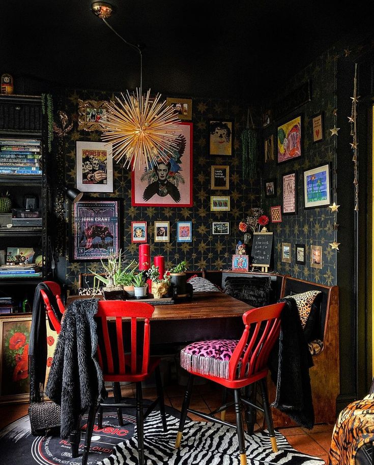 a dining room table with red chairs and pictures on the wall above it, along with other decor