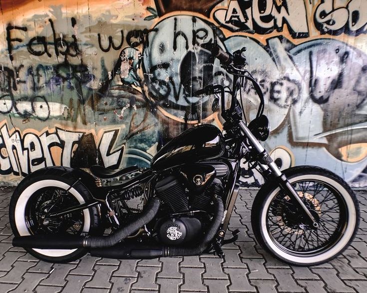 a black motorcycle parked in front of a wall with graffiti on it's walls