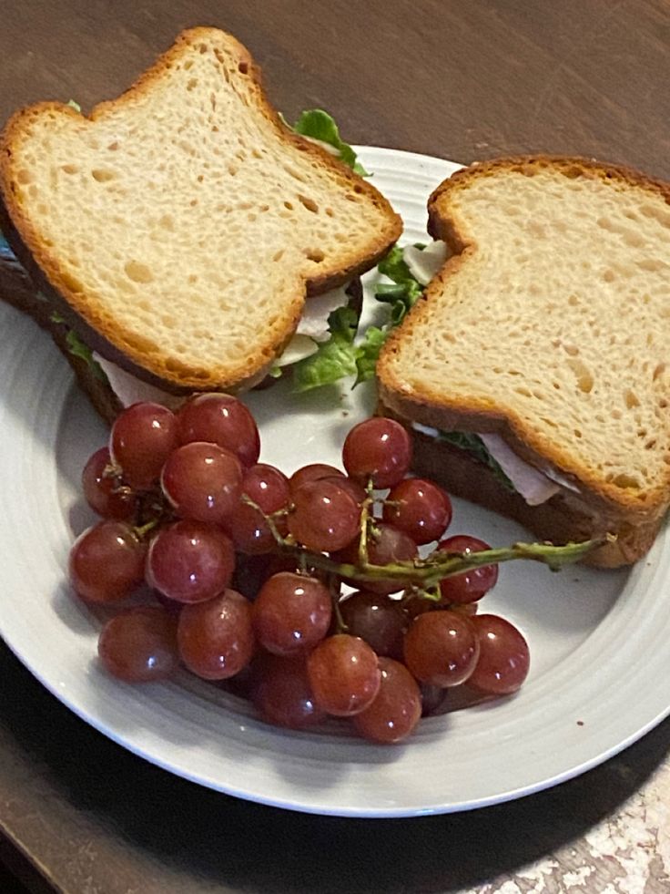 a sandwich and some grapes on a plate