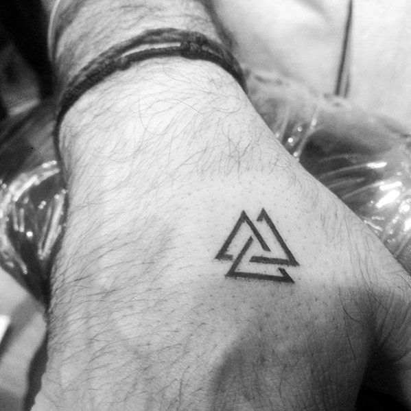 a man's hand with a small triangle tattoo on the left side of his arm