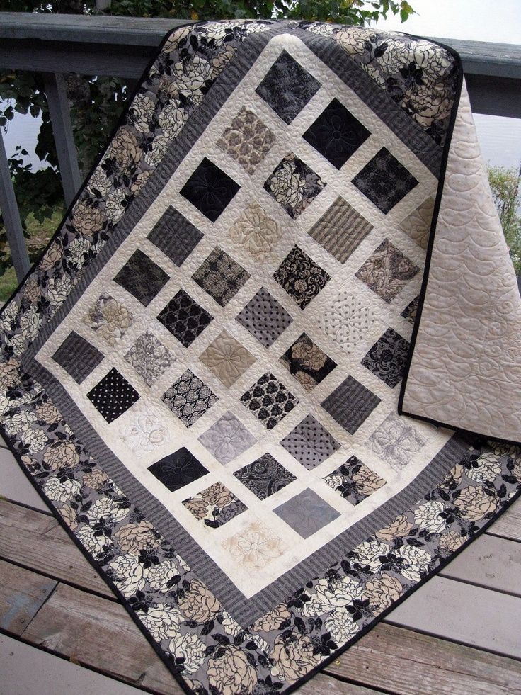 a black and white quilt sitting on top of a wooden deck