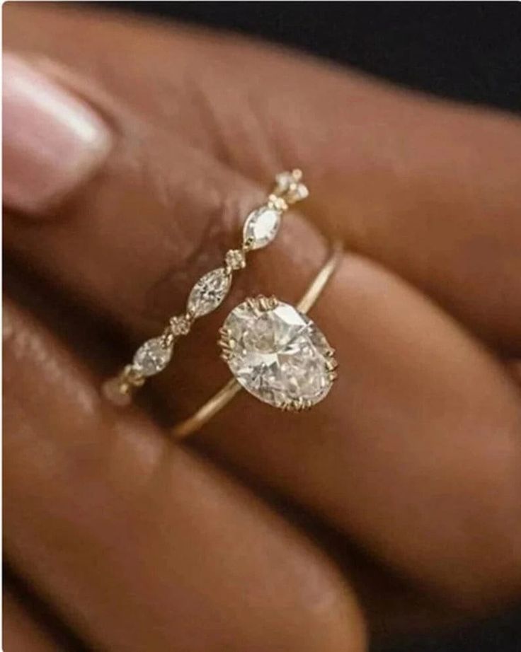 a woman's hand holding an engagement ring with two pear shaped diamonds on it