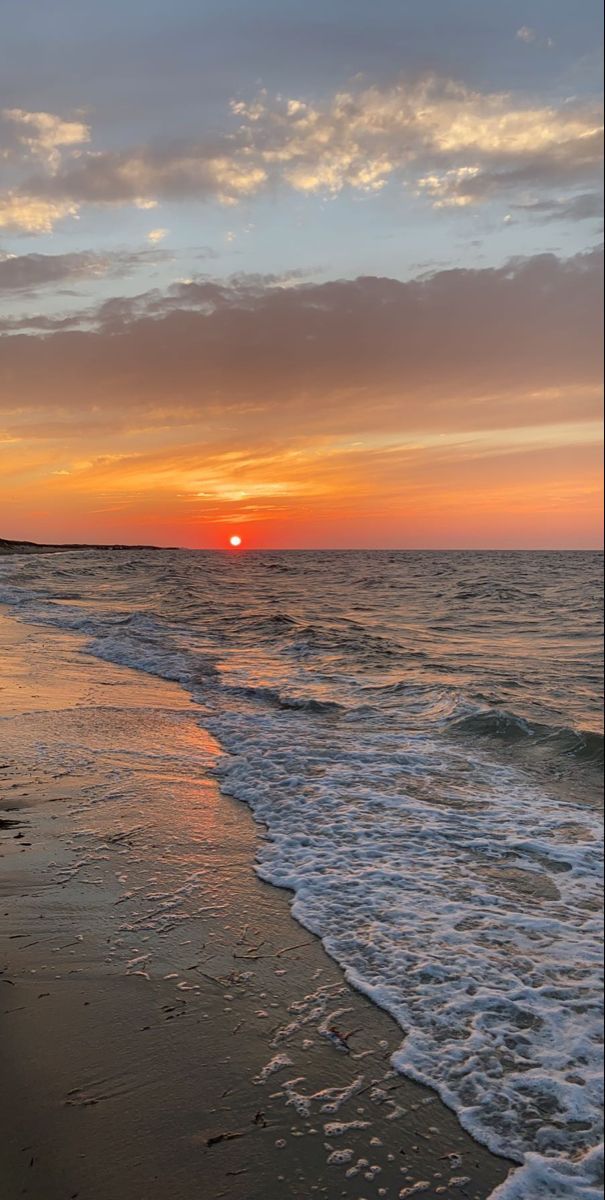 the sun is setting over the water at the beach