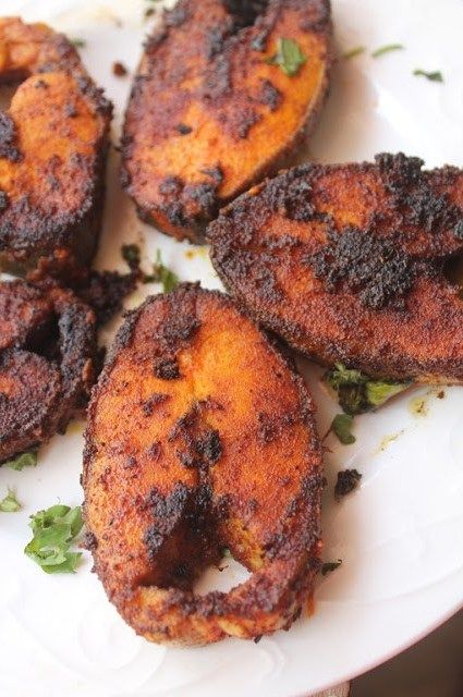 some fried food on a white plate with parsley sprinkled around the edges