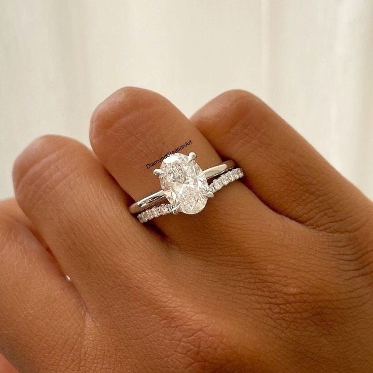 a woman's hand with a diamond ring on top of her finger and an engagement band