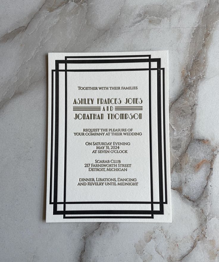 an elegant black and white wedding stationery on a marble background with the wording