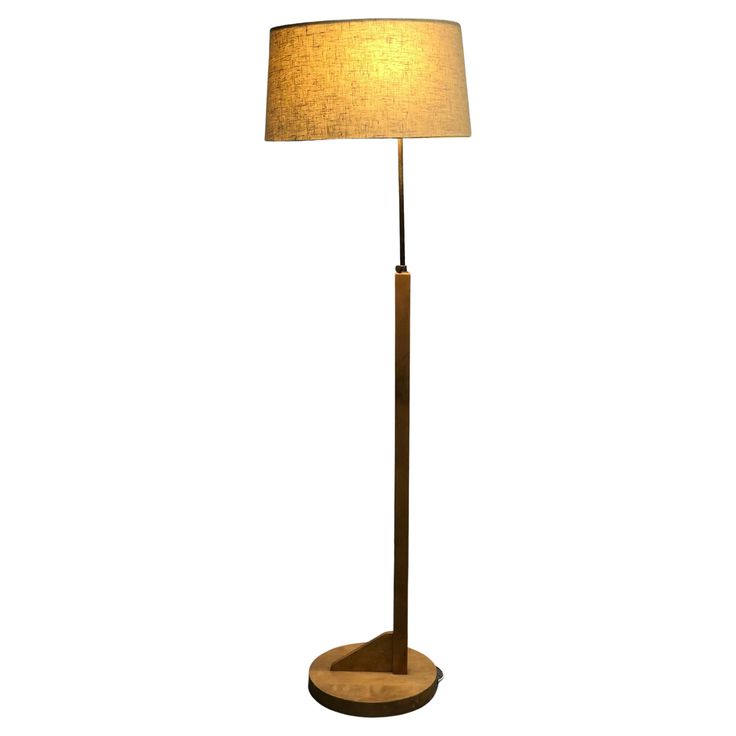 a wooden floor lamp with a beige shade on it's side and a white background