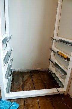 an empty refrigerator with the door open in a room that has wood floors and white walls