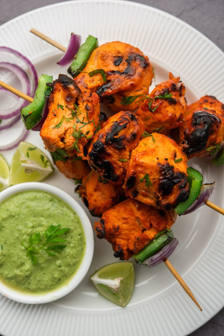 grilled chicken skewers with guacamole sauce on a white plate