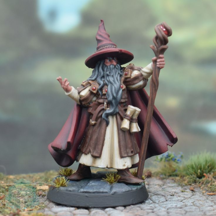 a wizard figurine holding a staff and wearing a red hat